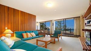 a living room with a blue couch and chairs at By The Sea Unit 4, 13 Esplanade, Kings Beach in Caloundra