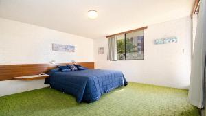 a bedroom with a blue bed and a window at By The Sea Unit 4, 13 Esplanade, Kings Beach in Caloundra