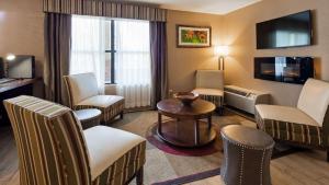 een hotelkamer met stoelen, een tafel en een tv bij Best Western Pine Springs Inn in Ruidoso Downs