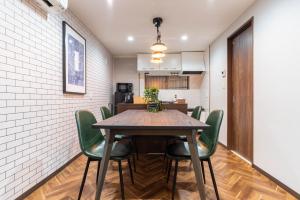 a dining room with a wooden table and green chairs at Harbor Light Tengachaya in Osaka