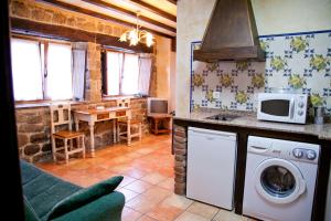 a kitchen with a washing machine and a microwave at Las Anjanas de Lloreda in Lloreda