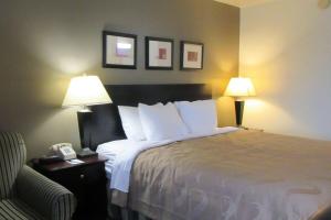 a hotel room with a bed with two lamps and a chair at Quality Inn in Longmont