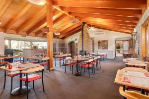 un restaurante con techos de madera, mesas y sillas en Quality Inn Carriage House, en Wagga Wagga