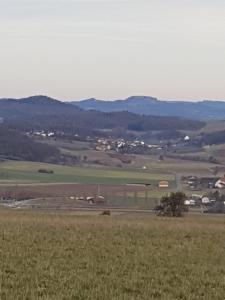 a view of a field with mountains in the background at Ferienwohnung Itzgrundruhe in Untermerzbach