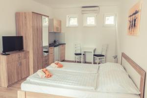 a bedroom with two white beds and a kitchen at Sekli Panzió in Balatonlelle