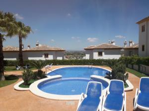 a swimming pool with blue chairs in front of a house at Quickcasaspain sl in Rojales +13 photos