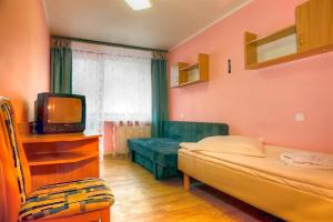 um quarto com uma cama, uma televisão e um sofá em Zdrowotel Łeba em Leba
