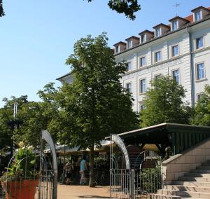 un grande edificio bianco con un albero di fronte di Hotel am Waldschlösschen - Brauhaus a Dresda