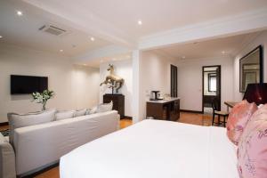 a living room with white furniture and a tv at The Bridge An Eclectic Luxotel in Chiang Mai