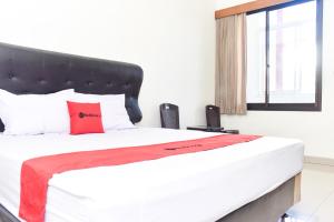 um quarto com uma cama grande e uma almofada vermelha em RedDoorz near Alun Alun Wonosobo em Wonosobo