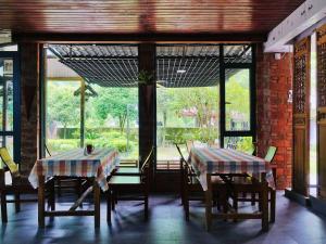 two tables and chairs in a room with windows at Xingping Our Inn in Yangshuo