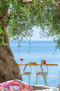 two chairs and a table in front of the ocean at Aurora Beach Hotel in Agios Ioannis Peristerion