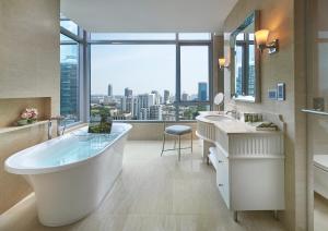 a bathroom with a large tub and a large window at Oriental Residence Bangkok - SHA Certified in Bangkok
