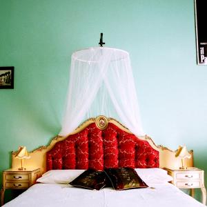un letto con testiera rossa e una croce sopra di esso di 5 Balconi B&B a Catania