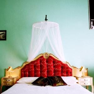 a bed with a red headboard with a cross above it at 5 Balconi B&B in Catania