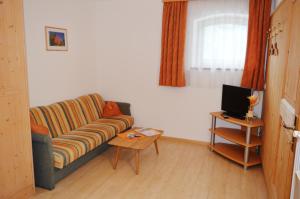 een woonkamer met een bank en een tafel met een tv bij Haus Kohler Bernhard in Nova Levante