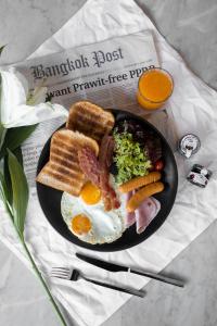 a plate of breakfast food with eggs bacon and toast at The Bridge An Eclectic Luxotel in Chiang Mai