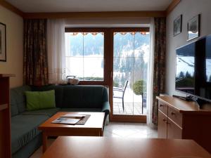 een woonkamer met een bank en een groot raam bij Lungau Apartment - Ferienwohnung Haus Esl in Hintergöriach