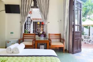 um quarto com 2 camas, uma mesa e cadeiras em HaLo HomeStay em Hoi An