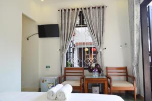 1 dormitorio con 2 sillas, mesa y ventana en HaLo HomeStay, en Hoi An