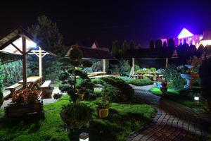 un jardín por la noche con un banco y una cruz en Hotel & Spa Arkadia, en Tomaszów Lubelski