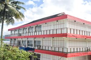 un bâtiment blanc et rouge avec un palmier dans l'établissement RedDoorz Plus @ Tirta Kencana Hotel, à Ambon