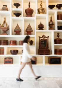 een vrouw loopt langs een tentoonstelling van aardewerk bij The Bridge An Eclectic Luxotel in Chiang Mai