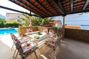 eine Terrasse mit einem Tisch, Stühlen und einem Pool in der Unterkunft Villa Skalinada in Baška Voda