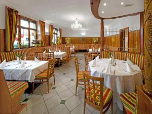 a restaurant with white tables and chairs and a chandelier at Hotel Linde in Donaueschingen