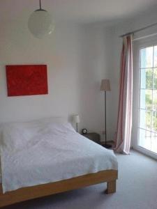ein weißes Schlafzimmer mit einem Bett und einem Fenster in der Unterkunft Ferienwohnung im Blauen Haus in Bad Suderode