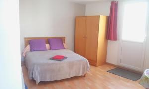 a bedroom with a bed with purple and purple pillows at pasteur in Cholet