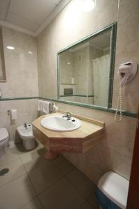 uma casa de banho com um lavatório, um WC e um espelho. em Hotel Joya em Benidorm