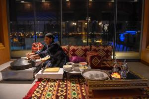 una mujer sentada en una mesa en una habitación con comida en The Palms Beach Hotel & Spa en Kuwait