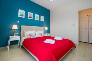 a bedroom with a red bed with a blue wall at Central Thassos Apartment 3 in Limenas