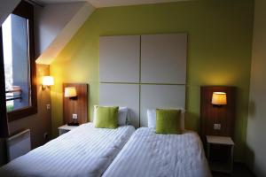 een slaapkamer met een groot bed met 2 groene kussens bij Hôtel Restaurant Du Parc de la Colombière in Dijon