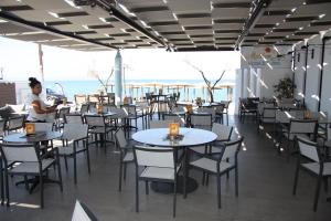 a restaurant with tables and chairs with the ocean in the background at Meliton Inn Hotel & Suites by the beach in Neos Marmaras
