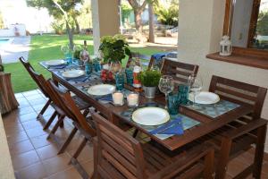 a wooden table with chairs and plates and wine glasses at Villa Sitges Colibri at 10 min Walk Beaches - Center City Amaizing Garden Pool XXL Private Tenis Piste in Vilanova i la Geltrú