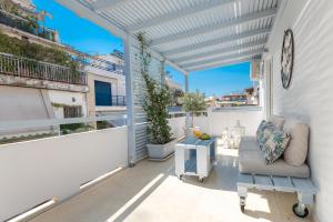 einen weißen Balkon mit Sofa und Uhr in der Unterkunft MeliDi Luxury Penthouse in Koukaki in Athen