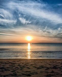 una puesta de sol en una playa con el océano en Apartments Isle of Pinecones, en Nida