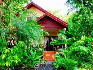 Une maison rouge avec une bande de plantes devant elle dans l'établissement Starbay Samui, à Lamai