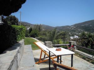 a white table and a chair on a patio with mountains at Blue Dolphin in Batsi