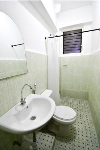 a white bathroom with a sink and a toilet at Casa Blanca Apartment in Manila