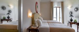 una camera d'albergo con due letti e uno specchio di Tombolo Talasso Resort a Marina di Castagneto Carducci
