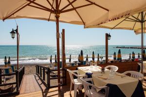 a restaurant on the beach with tables and umbrellas at Hotel Ristorante Il Gabbiano in Cecina