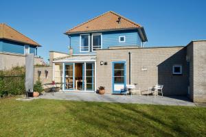 a blue house with chairs and a patio at Maxime 209 - Kustpark Village Scaldia in Hoofdplaat