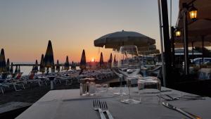 a table with wine glasses and chairs on the beach at Hotel Ristorante Il Gabbiano in Cecina