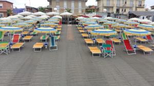 a row of chairs and umbrellas on a patio at Hotel Ristorante Il Gabbiano in Cecina