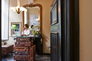 a woman talking on a cell phone in a room with luggage at Hotel Les Charmes in Maastricht