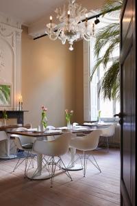 a dining room with tables and chairs and a chandelier at Hotel Les Charmes in Maastricht