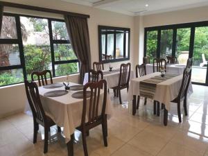 a dining room with tables and chairs and windows at Fourways BnB in Johannesburg